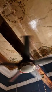 Декоративный расписной потолок в старой квартире-кафе: видны фрагменты росписи и потолочный вентилятор, сохраняющий историческую атмосферу интерьера.