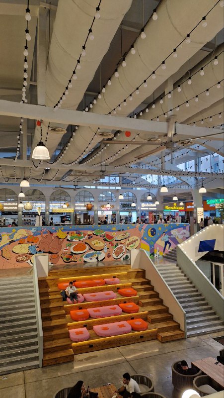 Просторный фудмолл с разноцветными сиденьями и зоной прилавков: интерьер Базари Орбелиани, много мест для сидения и торговых точек.