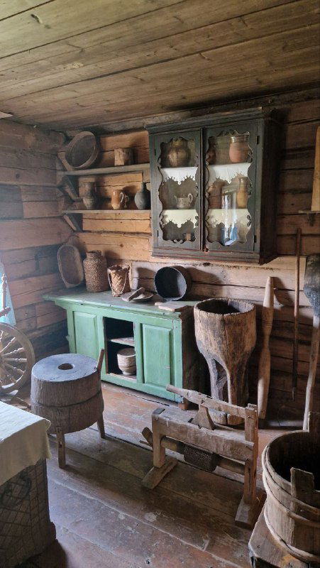 Интерьер крестьянской избы: деревянная мебель, полки с горшками, кухонная утварь и предметы ремесел — подробный снимок экспозиции быта.