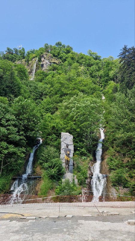 Каскад водопадов и скальный склон в Боржоми: зелёные деревья, каменные уступы и струи воды, падающие по склону.
