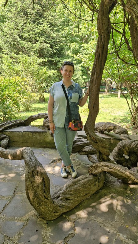 Автор поста стоит на извилистых корнях дерева в Боржомском парке: прогулочная зона с необычными корнями, зелёные насаждения вокруг.