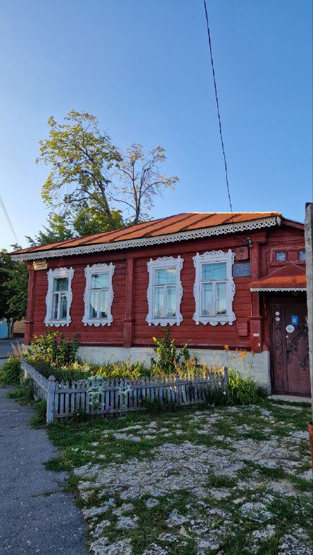 Низкий деревянный дом с резными наличниками на окнах и небольшим ограждением во дворе, архитектура купеческой провинции в Ельце.