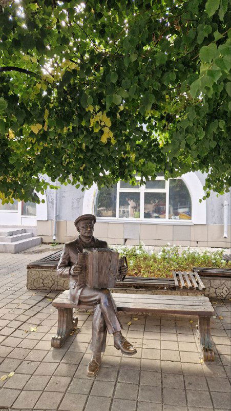 Скульптура гармониста, сидящего на лавочке, в тёплой уличной обстановке — жанровая композиция, подчёркивающая музыкальную традицию Ельца.