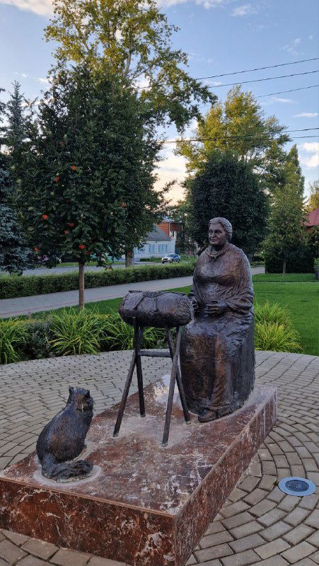 Скульптурная композиция елецкой кружевницы с котом рядом, размещённая в зелёном уголке города и отражающая ремесленную традицию региона.