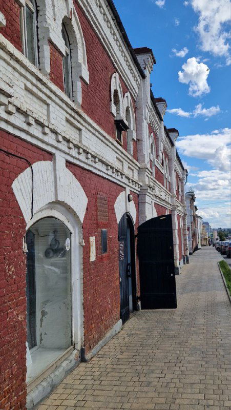 Ряд исторических кирпичных торговых рядов с арочными проходами, тротуар и фасады XIX века, отражающие торговое прошлое площади Ельца.