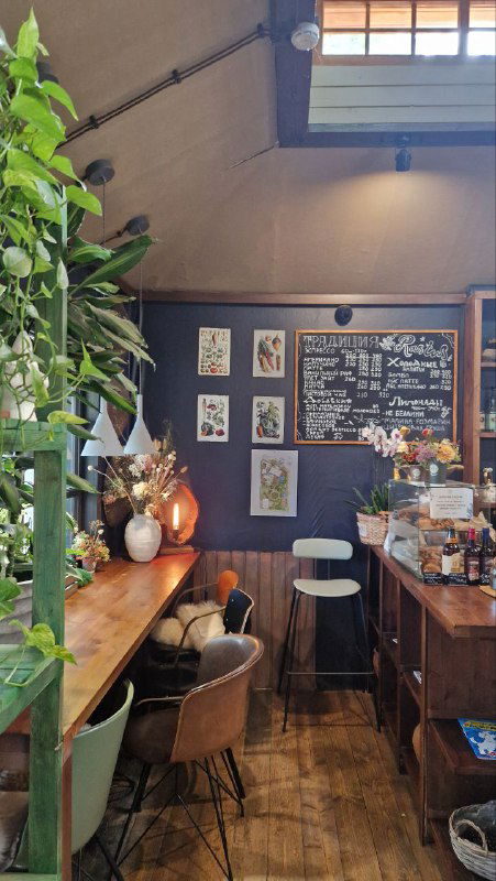 Уютная барная зона RastuS: деревянная стойка, меню на тёмной стене, барные стулья и композиции из цветов и керамики, тёплая атмосфера внутри.