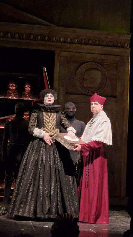 Эпизод с церемониальной сценой: актёры в исторических одеждах и фиолетово-красной сценографии, ощущение спектакля эпохи.