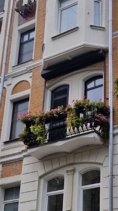 Фасад дома с балконом и цветочными ящиками возле Garda caffe — городской фон, создающий ощущение европейской улицы.