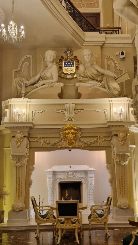 Архитектурная деталь интерьера: барельефы и скульптуры у лестницы, резные украшения и рельефный декор в зале кафе/особняка