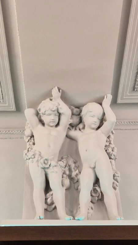 Деталь лепнины: белые херувимы/ангелочки на потолке, классическая декоративная скульптура в интерьере кафе или исторического здания