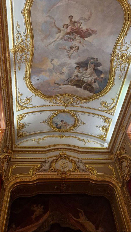 Росписи потолка и позолоченные декоративные элементы в зале Юсуповского дворца: фрагмент фрески с ангелами и сложной лепниной вокруг.