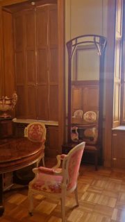Интерьерная комнатная сцена с антикварной мебелью: трюмо, стол и розовые стулья в уютной камерной комнате дворца с деревянным паркетом.