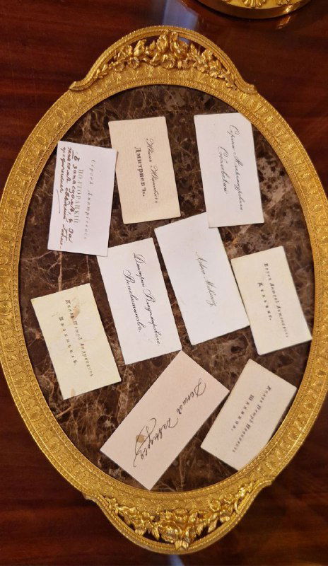 Поднос со старинными визитными карточками на столике у зеркала в приёмной комнате: каллиграфия и старинная бумага в интерьере музея.