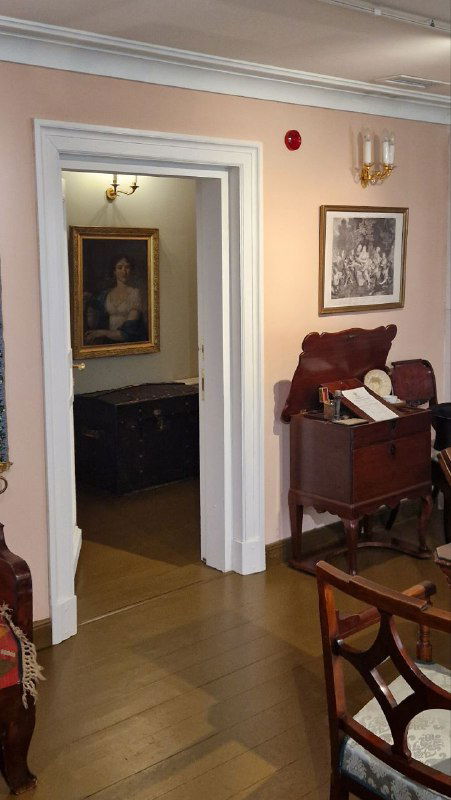 Интерьер комнаты с мебелью: резной стол, старинные кресла и портрет в глубине помещения — ощущение жилого пространства хозяина.