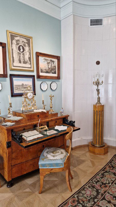 Рабочий стол и комод в библиотечной или кабинетной зоне: книги, письменные принадлежности и интерьер, близкий к интеллектуальной атмосфере хозяина.