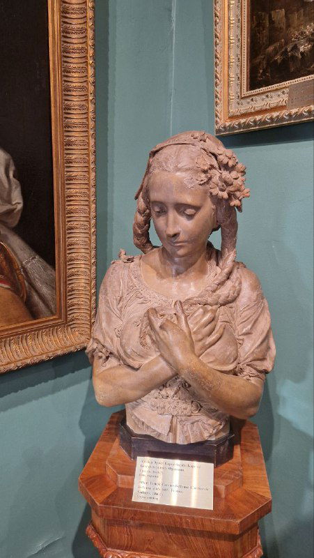 Скульптурный портрет молодой девушки на постаменте среди картин — одна из скульптурных работ в собрании Усадьбы Мараевых в Серпухове.