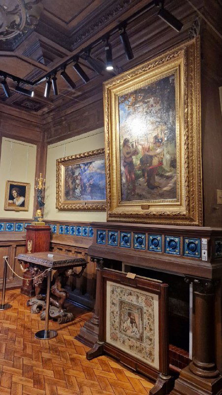 Интерьер зала с кафельной печью, крупными золотыми рамами картин и мебелью конца XIX века — характерная атмосфера усадебной экспозиции в Серпухове.