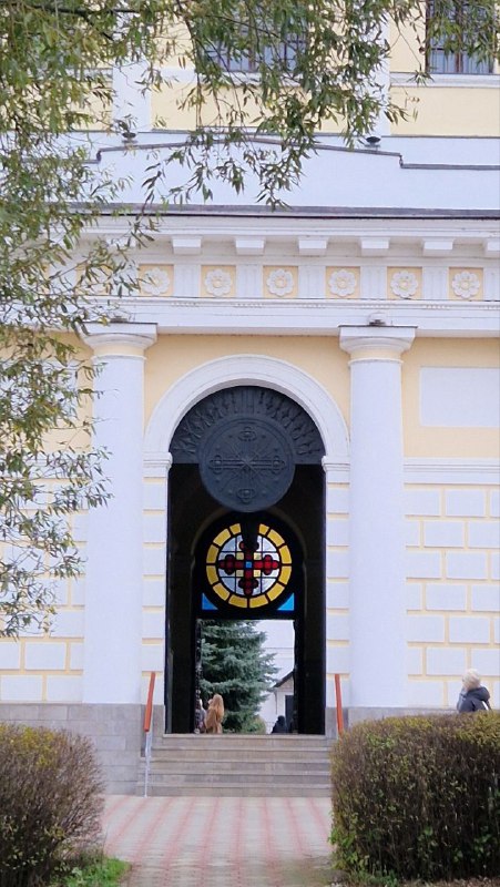 Арочный вход в историческое здание Серпухова с витражным окном и декоративной архитектурой, колонны и лепнина вокруг прохода.