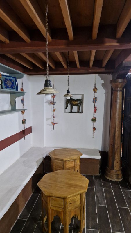 Интерьер с деревянной мебелью в этнопавильоне Этномира: низкие столики, табуреты и этнические декоры на стенах, уютная выставочная зона.