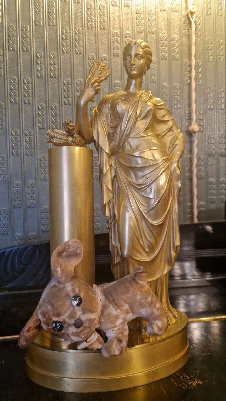 Статуэтка золотистого цвета с фигурой женщины и собачкой — декоративный предмет экспозиции в музей‑квартире с богатой отделкой.