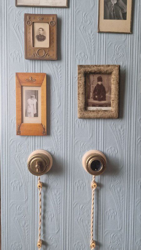 Стена с винтажными дверными ручками, семейными фотографиями и элементами декора — детали быта в музей‑квартире.