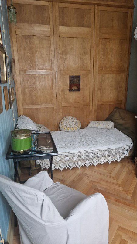 Уютный уголок с кроватью, покрывалом и деревянной панелью — часть жилой экспозиции, создающей ощущение присутствия хозяина.