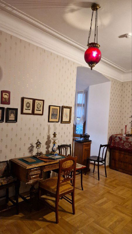 Интерьер комнаты в доме-музее: стол, стулья, люстра и элементы оформления конца XIX века, тёплая музейная обстановка