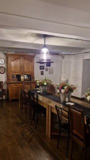 Интерьер антрактного пространства: длинный деревянный стол, стулья и вазы с цветами под приглушённым светом в театральном фойе.