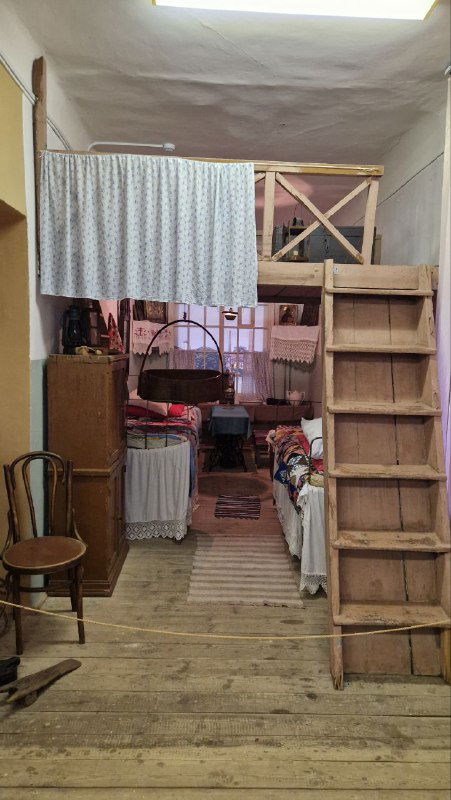 Вид внутри казарменной «коморки»: деревянные полки, лестница и спальные места, показывающие тесные условия жизни рабочих фабрик.