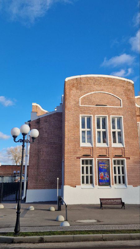 Фасад Зимнего театра Орехово-Зуево: кирпичное здание с высокими окнами и декоративными элементами на фоне ясного неба.