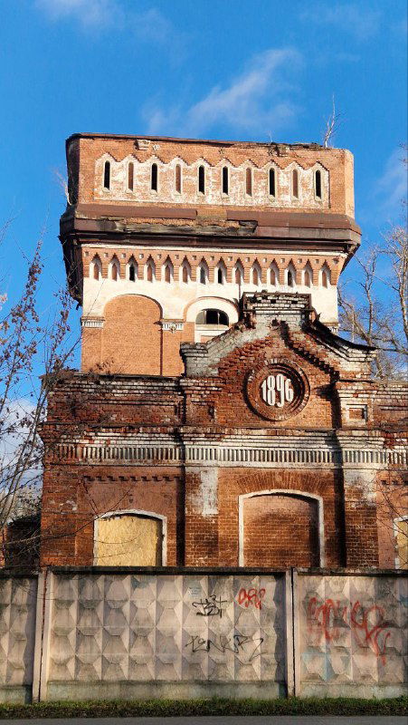 Водонапорная башня Орехово-Зуево — массивная кирпичная промышленная постройка с историческими декоративными элементами на фоне неба.