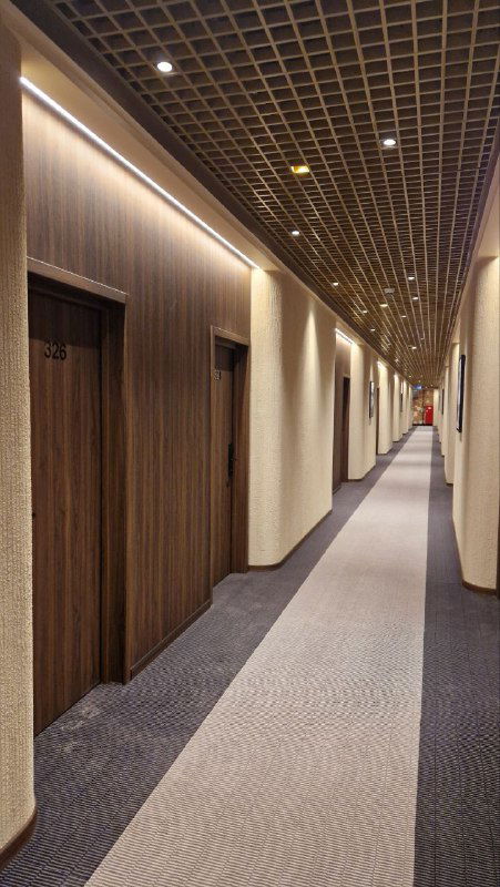 Длинный гостиничный коридор AZIMUT с дверями номеров, мягкой подсветкой и современным потолком — спокойный интерьер для прогулок по отелю.