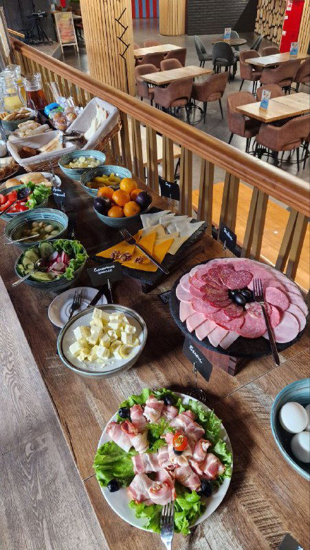 Шведский стол в фуд‑холле Стачка: тарелки с нарезками, сыры, салаты и фрукты на длинной сервировочной поверхности на первом этаже.