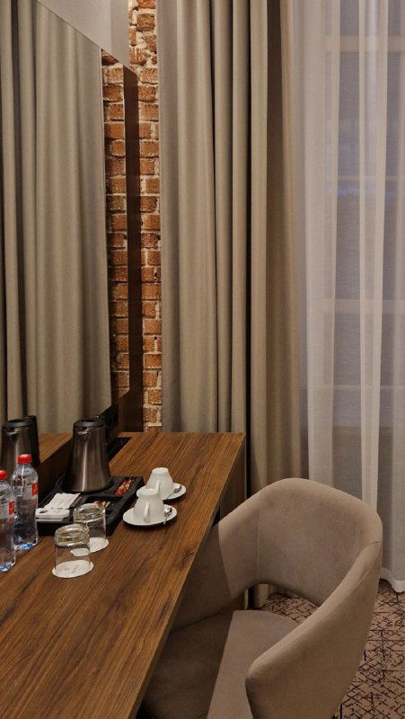 Рабочее место у окна в номере: стол с чайником и бутылками воды, широкий подоконник, пригодный для сидения и работы во время поездки.