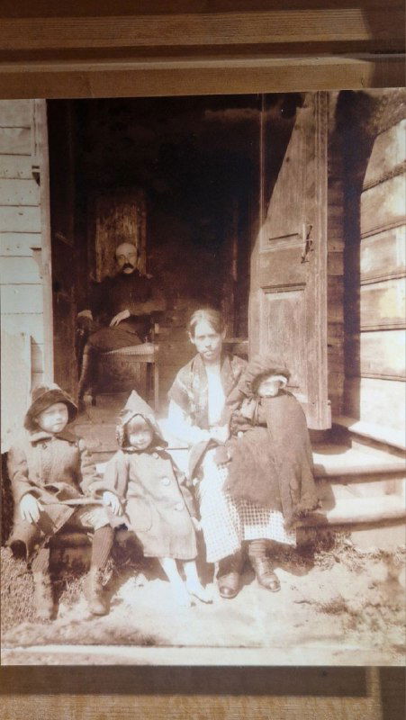 Старинная чёрно-белая семейная фотография с детьми и няней на ступенях дома, экспонируемая в музее Цветаевых, документальная атмосфера