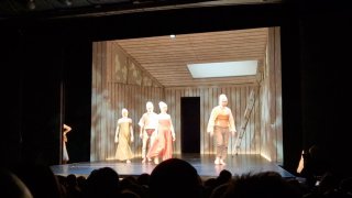 Сцена пластического спектакля: светлая комната с актёрами и куклами на сцене, видны костюмы в духе Брейгеля и взаимодействие пластики и кукол.