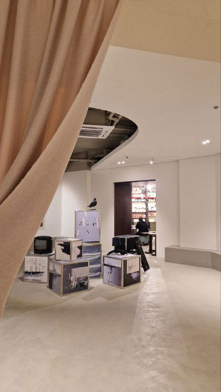 Магазинная витрина и коробки с брендированной продукцией Moodrā Shop у входа: концептуальный корнер с товарами и сувенирами в минималистском стиле.