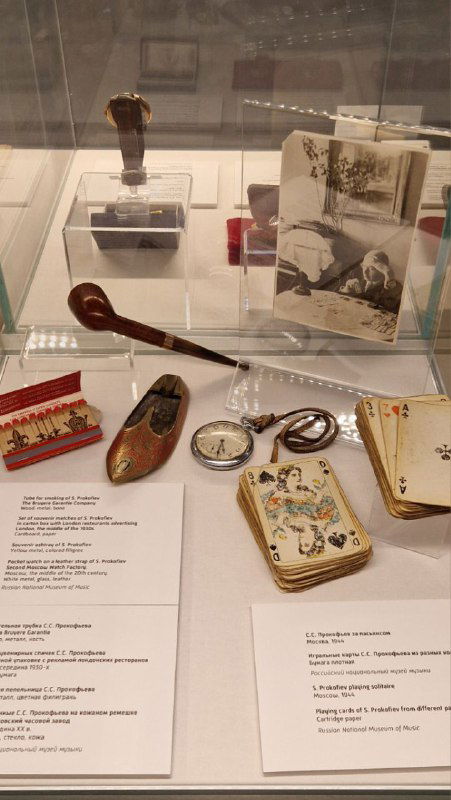 Витрина с личными вещами Прокофьева: карманные часы, дорожные аксессуары и сувенирные предметы с подписями экспозиции в музее композитора.