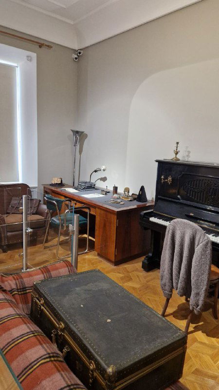 Рабочий кабинет композитора в музее: письменный стол у окна, стул и чемодан, передающие домашнюю атмосферу и творческое пространство Прокофьева.