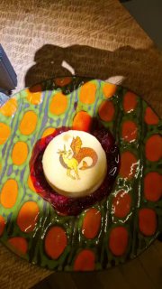 Авторский десерт на цветной тарелке: круглая порция с украшением и соусом, крупный план, показывающий художественную подачу и текстуру блюда.