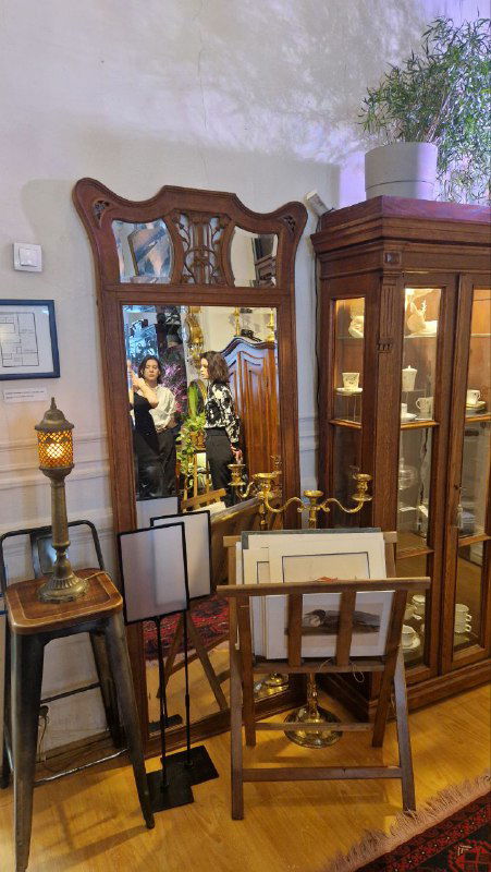 Уголок с большим зеркалом и витриной в антикварной галерее: отражения мебели и предметов интерьера, подготовка сценической атмосферы спектакля.