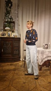 Актриса на сцене в интерьере дома Прозоровых: бытовая обстановка, лампа на столе и сдержанная актёрская манера в близком плане сцены.