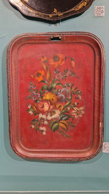 Крупный план красочного жостовского подноса с букетом цветов на красном фоне, пример традиционной цветочной росписи.