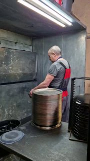 Рабочая сцена в цехе: кузнец или мастер устанавливвает металл для изготовления заготовок под подносы в производственном помещении.