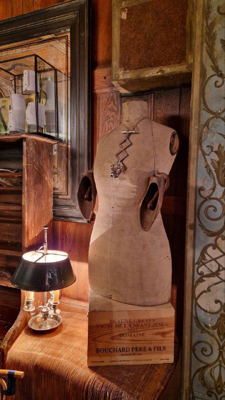 Манекен-торс в ретро-атмосфере рядом с лампой и текстильным оформлением — неожиданный театральный элемент декора ресторана.