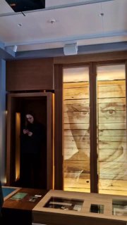 Инсталляция в музее «Первая дача»: посетитель у открытого шкафа рядом с деревянными панелями, на которые проецируется лицо и тени.