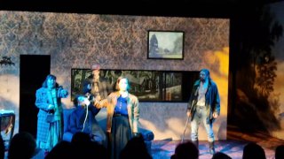 Групповая сцена с актёрами под яркими прожекторами: динамичное исполнение и хоровые номера на минималистичной сцене.