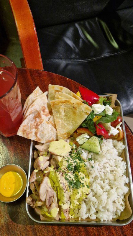 Контейнер с рисом, лепёшками, овощами и соусами — пример полноценного блюда в стиле стритфуда в баре, поданное в металлическом лотке.