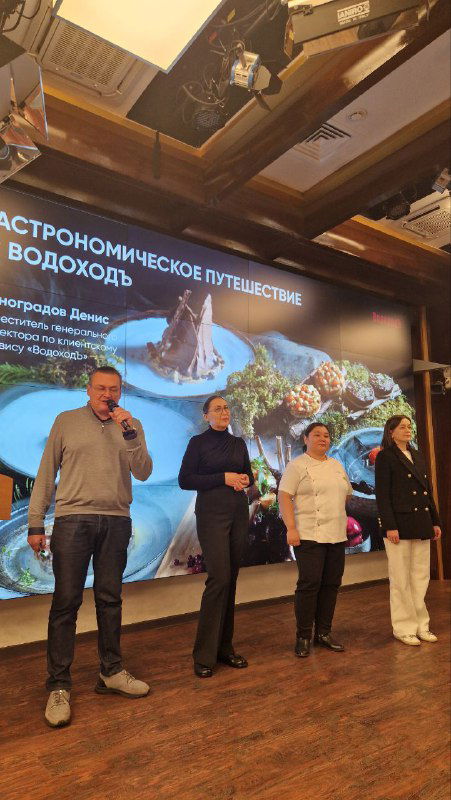 Группа выступающих на сцене на фоне слайдов «Гастрономическое путешествие с Водоход», спикеры рассказывают о меню экспедиций.