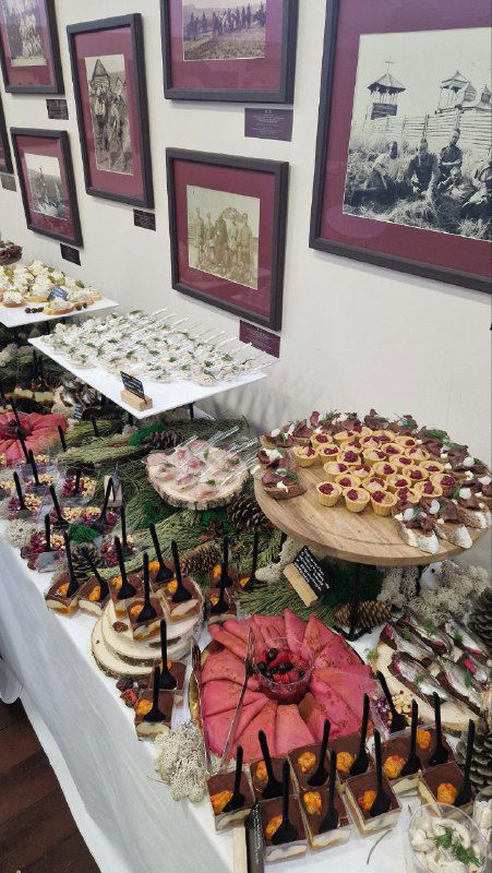 Разнообразные закуски и десерты на столе выставки: тарелки с угощениями, оформленные для дегустации гостями мероприятия.